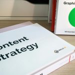 Books on content strategy and graphic design essentials resting on a wooden desk.