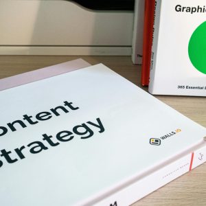 Books on content strategy and graphic design essentials resting on a wooden desk.