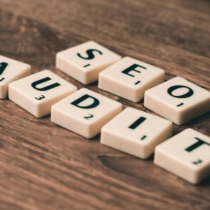 Scrabble tiles spelling SEO Audit on wooden surface, symbolizing digital marketing strategies.