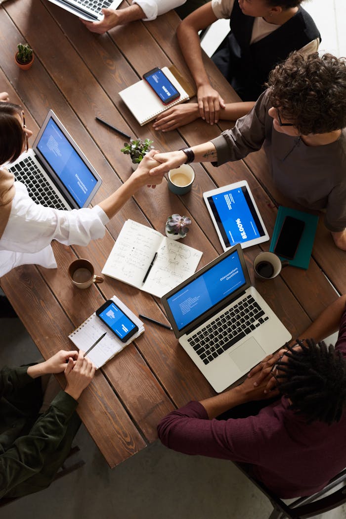 who-we-are A diverse group of professionals brainstorming in a modern workspace with laptops and notebooks.