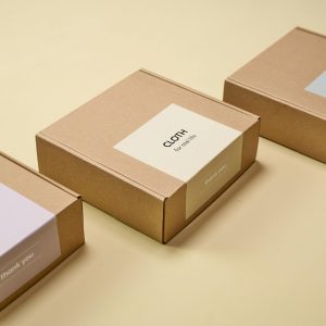 Three minimalist cardboard packages labeled 'CLOTH' on a yellow background.